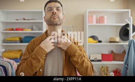 Ein stilvoller hispanischer Mann passt seine braune Jacke in eine helle, moderne Garderobe mit verschiedenen Kleidungsstücken. Stockfoto