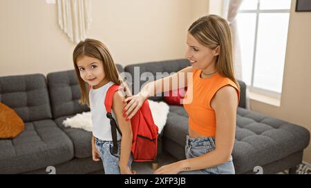 Mutter hilft der Tochter, den Rucksack drinnen zu tragen und zeigt Liebe und Familie in einem gemütlichen Zuhause. Stockfoto