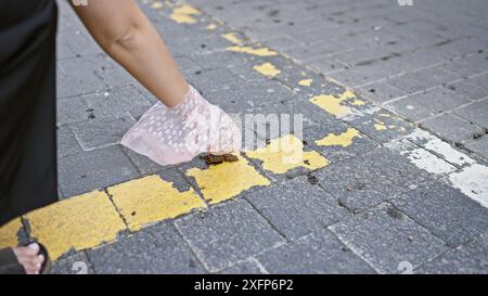 Eine Frau sammelt Hundeabfälle auf einer Stadtstraße auf, um Sauberkeit und Verantwortung zu veranschaulichen. Stockfoto