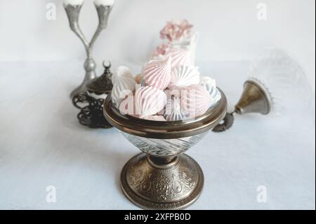 Kleine farbige Baisons in einer schönen Glasschale auf einem Bein im orientalischen Stil auf einem Tisch. Kopierbereich. Stockfoto