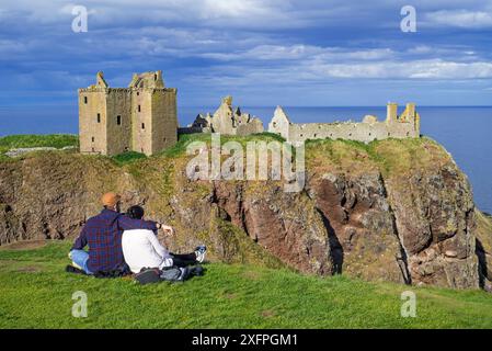 Touristen schauen sich Dunnottar Castle an, eine ruinierte mittelalterliche Festung in der Nähe von Stonehaven auf einer Klippe entlang der Nordseeküste, Aberdeenshire, Schottland, Großbritannien, Mai 2017 Stockfoto