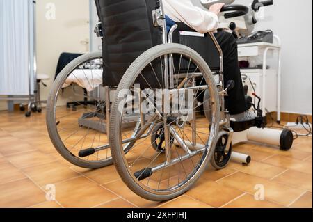 Eine nicht erkennbare ältere Frau macht Pedalübungen vom Rollstuhl aus im Krankenhaus. Hochwertige Fotos Stockfoto