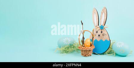 Osterhasen oder Kaninchen, die neben einem Korb mit bunten Eiern sitzen, Frühlingsferien Stockfoto