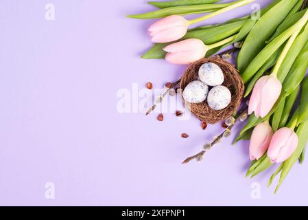 Ostereier in einem Vogelnest, rosa Tulpen, Weihnachtsgrußkarte, Hintergrund der Frühlingssaison Stockfoto