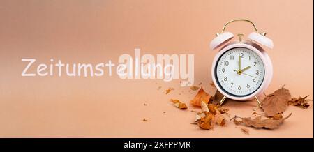 Wecker mit Herbstlaub, Ende der Sommerzeit im Herbst, WINTERWINTERWARNWECHSEL steht in deutscher Sprache neben der Uhr Stockfoto