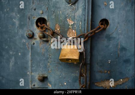 Alte verwitterte Tür mit einem Vorhängeschloss und einer rostigen Kette verschlossen Stockfoto