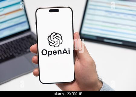 PRAG, TSCHECHISCHE REPUBLIK - 21. JANUAR 2024: Öffnen Sie das KI-Logo auf dem Bildschirm des Smartphones in der Hand des Mannes auf dem Hintergrund des Arbeitsplatzes. Stockfoto