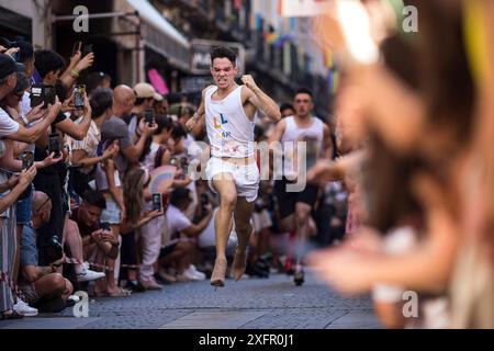 Madrid, Spanien. Juli 2024. Die Teilnehmer laufen während des Heel Race in der Pelayo Street mit High Heels. Im LGTBIQ-Viertel Chueca fand die 25. Auflage des Heel Race statt, ein sportlich-festlicher Test, bei dem die Teilnehmer mit bis zu 15 Zentimeter hohen Heels laufen müssen. Quelle: SOPA Images Limited/Alamy Live News Stockfoto