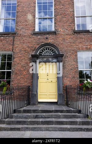 Ein historisches Backsteinhaus mit gelber Tür in Kilkenny, Irland. Stockfoto