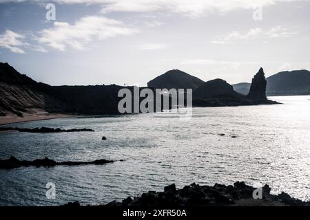 Ein atemberaubender Blick auf die Küstenlandschaft von Galapagos mit zerklüfteten Küsten und entfernten Vulkangipfeln, die die ruhige und dramatische Landschaft einfangen. Stockfoto