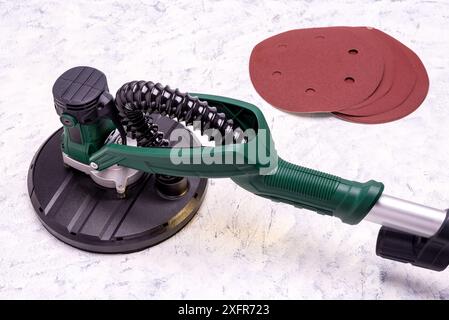 Wandschleifer mit Teleskopgriff und LED-Licht und Schleifpapier zum Glätten und Schleifen von Wänden auf grauweißem Hintergrund. Stockfoto