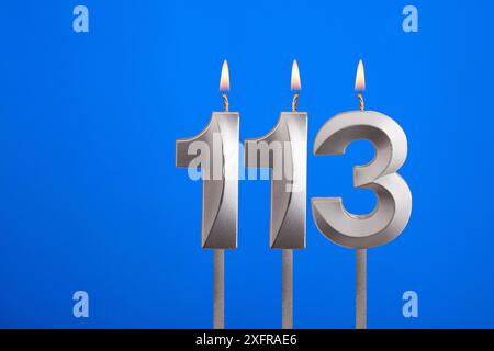 Geburtstagskerze Nummer 113 - Geburtstagskarte auf blauem Hintergrund Stockfoto