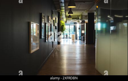 Moderner Büroflur mit gerahmter Kunst an den Wänden und natürlichem Licht aus den Fenstern Stockfoto