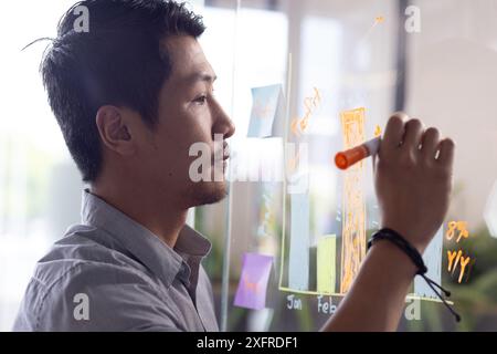 Schreiben auf transparenter Tafel, Mann analysiert Daten und erstellt Geschäftsstrategien Stockfoto