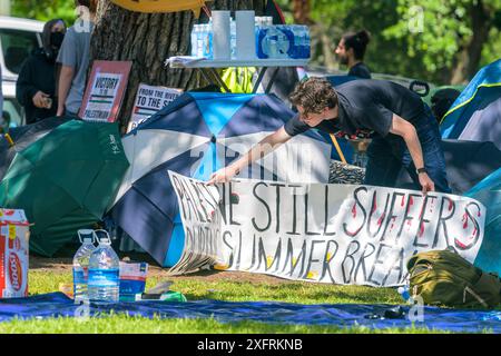 NEW ORLEANS, LA, USA – 30. APRIL 2024: Pro-palästinensischer Demonstrant richtet ein Banner mit der Aufschrift „Palästina leidet noch während der Frühlingsferien“ auf. Stockfoto