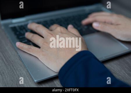 Ein Nahbild der Hände einer Person, die auf einer Laptop-Tastatur tippen. Produktivität, Arbeitsaufwand und Arbeitskonzept. Stockfoto