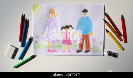 Foto der Kinderzeichnung mit Farbstiften. Das Bild zeigt die Familie. Mom, Dad und Mädchen laufen in der Natur. Büroausstattung, Bleistifte, Spitzer, e Stockfoto