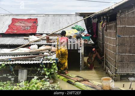 Morigaon, Assam, Indien. Juli 2024. MORIGAON, ASSAM, INDIEN-04. JULI 2024: Eine Frau trocknet ihr Tuch auf dem Dach eines überfluteten Dorfes im Morigaon District in Assam. (Kreditbild: © Hafiz Ahmed/ZUMA Press Wire) NUR REDAKTIONELLE VERWENDUNG! Nicht für kommerzielle ZWECKE! Stockfoto