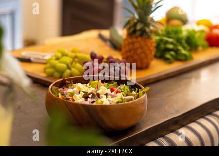 Frischer Salat in Holzschale mit Obst und Gemüse auf der Küchenzeile, Kopierraum Stockfoto
