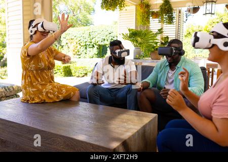 Mithilfe von VR-Headsets genießen verschiedene Freunde gemeinsam das Virtual-Reality-Erlebnis in Innenräumen Stockfoto