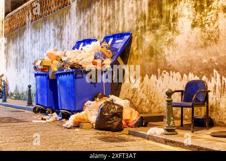 Übergelaufene Mülltonnen. Blick auf Mülltonnen auf der Nachtstraße. Stockfoto