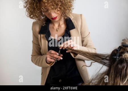 Junge Frau mit lockiger Frisur zufrieden nach dem Färben von Haarspitzen im Salon Stockfoto