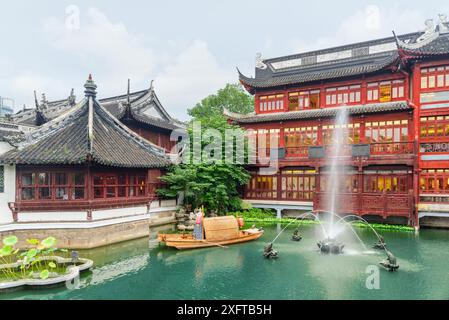 Herrlicher Blick auf den Brunnen inmitten eines malerischen Teichs zwischen traditionellen chinesischen Gebäuden mit schwarz geschwungenen Dächern in der Altstadt von Shanghai. Stockfoto