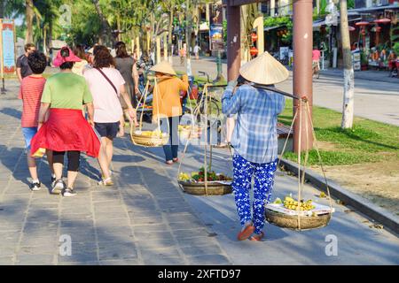 Hoi an (Hoian), Vietnam - 11. April 2018: Vietnamesische Straßenverkäufer laufen unter Touristen in der antiken Stadt Hoi an. Stockfoto