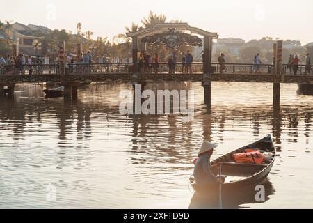 Hoi an (Hoian), Vietnam - 11. April 2018: Vietnamesische Frau in traditionellem Bambushut auf dem Boot bei Sonnenuntergang. Stockfoto