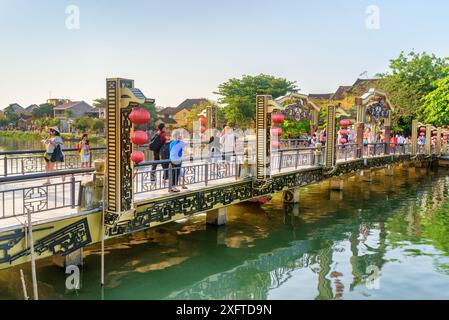 Hoi an (Hoian), Vietnam - 11. April 2018: Touristen wandern entlang der malerischen Brücke, die mit traditionellen roten Seidenlaternen dekoriert ist, in der antiken Stadt Hoi an. Stockfoto