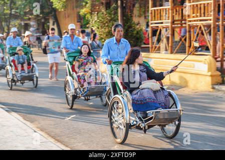 Hoi an (Hoian), Vietnam - 11. April 2018: Touristen reiten Trischas (Radrikschas) in der antiken Stadt Hoi an. Stockfoto