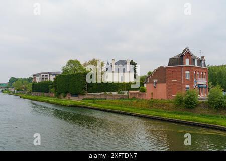 Cambrai, Frankreich - 21. Mai 2023: Ein malerischer Blick auf einen Kanal in Cambrai, Frankreich, mit üppigem Grün, charmanten Häusern und einem ruhigen Wasserweg. Stockfoto