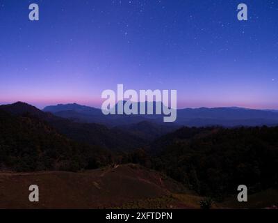 Doi Luang Chiang Dao Berg bei Nacht unter blauem Himmel mit Sternen und dunklem Tal in Chiang Mai - Nordthailand Stockfoto