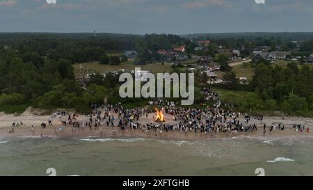 Feier der Mittsommerferien (Ligo) in Pavilosta, Lettland. Viele unerkannte Leute stehen an einem brennenden Feuer in einer Sommernacht im Stockfoto