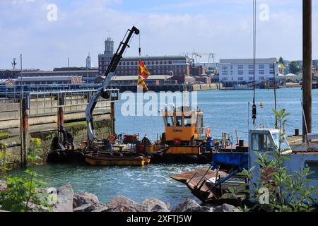 27. Juni 2024. Ein Schlammbagger mit Kran und Arbeitern im Gosport Harbour. Stockfoto