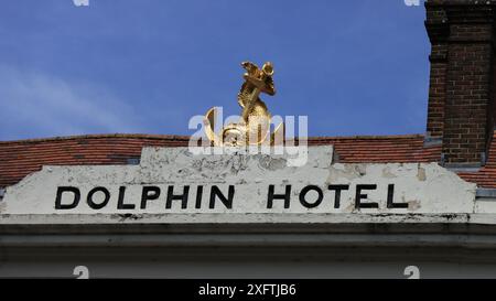 Chichester, West Sussex, England. 27. Juni 2024. Weitwinkelblick auf die Fassade des Dolphin Hotel in Chichester mit Golddelfin und Ankerskulptur. Stockfoto