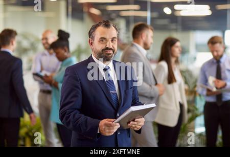 Reifer seriöser Geschäftsmann, Erwachsener Teamleiter, männlicher Mentor unter verschiedenen Geschäftsleuten im Amt Stockfoto