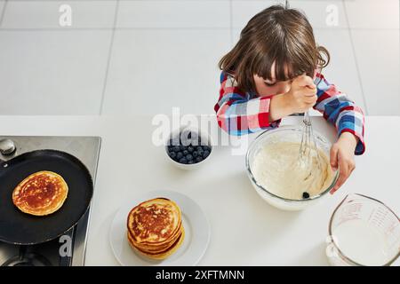 Kinder, Backen und Toppen oder Rühren zu Hause, Zutaten und Mischen Schüssel oder Pfannkuchenteig in der Morgenküche. Kulinarische Fähigkeiten, Junge und Mischung oder Kochen Stockfoto