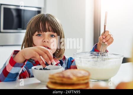 Junge, Backen und Rühren in der Küche, Zutaten und Mischen Schüssel oder Pfannkuchenteig im Morgenporträt. Kulinarische Fähigkeiten, blaue Beeren und Kochen Stockfoto