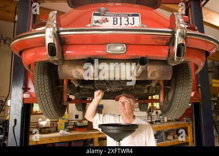 Ein Mann arbeitet an seinem antiken Sportwagen in seiner Garage in Pennsylvania. Stockfoto