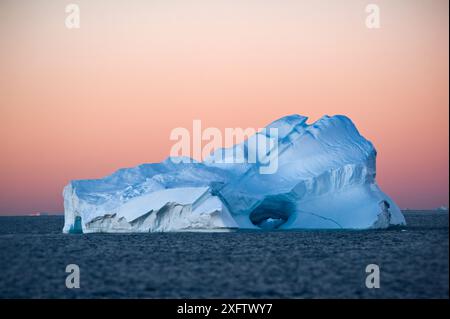 Immer größer werdende Eisberge brechen vom Land ab und machen sich dort auf den Weg ins Meer. Die wunderschönen Kunstwerke aus der Natur tragen ironische Schönheit bei Sonnenuntergang bei Vollmond. Stockfoto