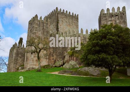 18.02.2014 Guimarães, Portugal - die Burg von Guimarães scheint unter der hellen Sonne unter blauem Himmel und üppigem Grün Stockfoto