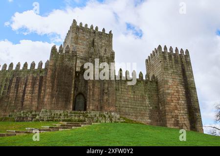 18.02.2014 Guimarães, Portugal - die Burg von Guimarães scheint unter der hellen Sonne unter blauem Himmel und üppigem Grün Stockfoto