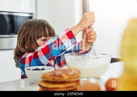 Junge, Backen und Rühren in der Küche, Zutaten und Mischen Schüssel oder Pfannkuchenteig in der Morgenwohnung. Kulinarische Fähigkeiten, Utensilien und Kochen Stockfoto