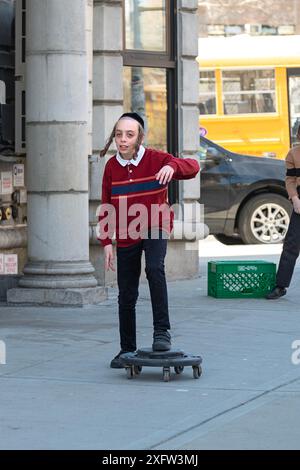 Während der Pause in einer jüdischen Pfarrschule rollt ein Junge auf einem improvisierten Spielzeug herum. In Brooklyn, New York. Stockfoto