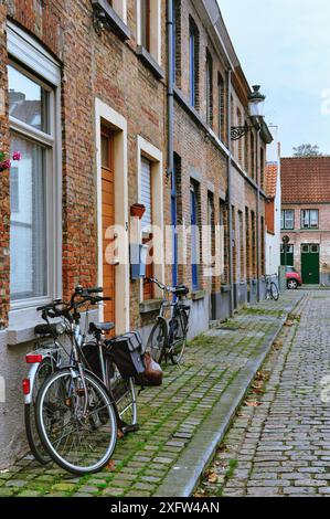 30-10-2014 Brügge, Belgien - Eine malerische Kopfsteinpflasterstraße in Brügge mit Fahrrädern, die an Haustüren geparkt sind Stockfoto