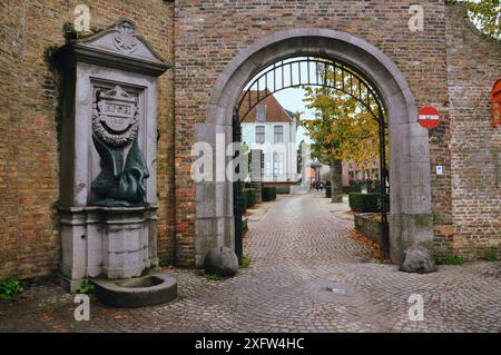 30-10-2014 Brügge, Belgien - Kopfsteinpflasterstraße mit Tor und Skulptur im malerischen Brügge Stockfoto