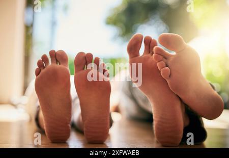 Füße, Paar und Etage zum Entspannen zu Hause, Wohnzimmer und Holzboden für Ruhe und Frieden. Vertrauen, Unterstützung oder Einheit in der Beziehung für verheiratete Menschen Stockfoto