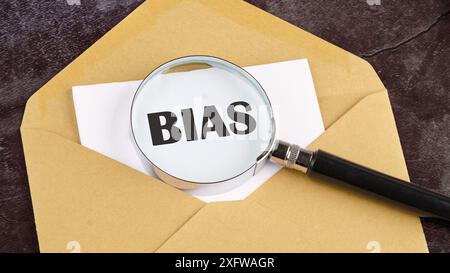 Persönliche Meinungen nehmen das Vorurteilskonzept durch eine Lupe auf einem Blatt Papier vor, das aus einem Umschlag heraussteht. Konzeptfoto Stockfoto