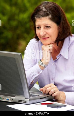 Pensionierte Frau mit Laptop-Computer in ihrem Garten Stockfoto